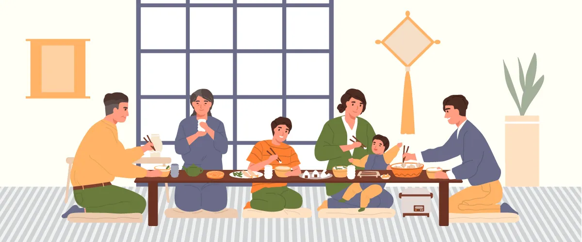 Six personnes d’âges différents assises au sol, prenant un repas à une longue table basse.