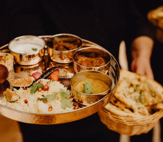 Photo d’un thali indien et un panier en osier contenant des pains naans.
